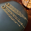 Detailed view of long gold tassel earrings with heart-shaped studs on green jewelry box - Gold Sequin Tassel (29# Earring Clasp)