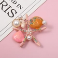 Spilla stella marina rosa con strass colorati, conchiglie e perle su uno sfondo rosa liscio - Rosa