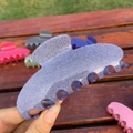 Sparkling purple acetate hair claw clip with seven teeth shown in hand against garden background - Seven Teeth Claw / Purple-Blue Glitter