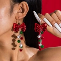 Boucles d'oreilles nœud de Noël avec clochettes colorées portées par un mannequin en studio - Noeuds Cloches Rouges