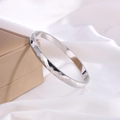 Macro shot of silver titanium steel bracelet with diamond-cut texture on white silk - Silver