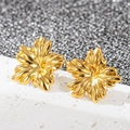 Vue macro de boucles d'oreilles fleurs en acier inoxydable doré sur une pierre blanche - Tournesol