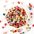 Colorful square acrylic alphabet beads with gold letters in a white petal-shaped bowl - 6x6mm Colored Base With Gold Letters (100pcs)