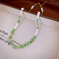Detailopname van groene kralen en witte parels ketting op een beige sieradenplateau - 12# Ketting-Retro Parel Groene Kralen
