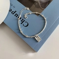Silver bead bracelet with engraved square charm on light blue book background - Square Tag Silver Bracelet