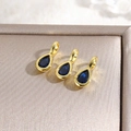 Detailed close-up of three gold 18k plated waterdrop pendants with blue zircon stones - Blue