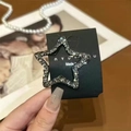 Detailed close-up of a silver star hair clip with shimmering dark rhinestones - Black