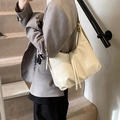 Sac cabas rétro en cuir blanc crème avec pompon porté par un mannequin en mode décontracté - Blanc