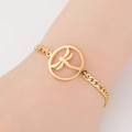 Detail of a gold titanium steel bracelet with a hollow dragonfly charm worn on the wrist - Dragonfly / Gold