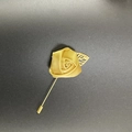 Detail of handmade gold satin rose brooch with metallic leaf on dark textured background - Gold