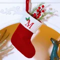 Red knit Christmas stocking with embroidered letter M hanging on a white fireplace - Letter M / Red