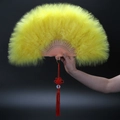 Detailed view of yellow feather folding fan with carved ribs and red tassel decor - Yellow
