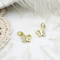 Macro shot of gold butterfly charms with white zircon inlay on white lace background - Butterfly