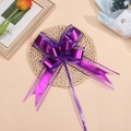 Close-up of a double-layered purple gift bow with matte metallic ribbons on a woven mat - Purple