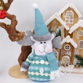 Detail of Christmas reindeer plush toy with blue knit hat and scarf on desktop - Reindeer