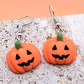 Vue macro de boucles d'oreilles citrouille d'Halloween en résine sur surface de pierre - Visage de citrouille