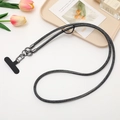 Detail of dark gray woven phone lanyard with metal clasp and black tether tab shown on desk - Black