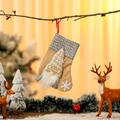Linen Christmas stocking with gnome decoration and HO HO HO text hanging on a tree branch - Beige