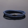 Detailed view of blue braided cord bracelet with black magnetic clasp on reflective surface - Navy Blue