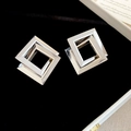 Makro-Detail von silbernen geometrischen quadratischen Ohrringen auf Samt - Silber