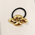 Détail d'un élastique à cheveux avec une grande fleur dorée à sept pétales - Anneau Métallique Minimaliste