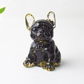 French bulldog resin statue with black body and gold leaf accents on white background - Obsidian