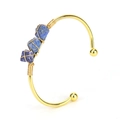 Close-up of three blue natural raw stones wire-wrapped on a golden open cuff bracelet - Lapis Lazuli