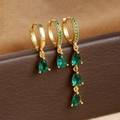 Macro shot of three-piece gold drop earrings with green zircons on leather display - Gold-Green