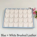 Detailed view of a 24-compartment jewelry display tray in blue with white leather lining - Blue + White Brushed Leather