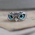 Vintage silver owl ring with deep blue eyes on a textured paper background - Blue