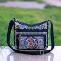 Detail of colorful floral peacock embroidery on black canvas bag with metal zipper - Money Tree Red
