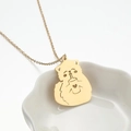 Dettaglio della collana con ciondolo a gatto in acciaio dorato su un piatto in ceramica - Oro