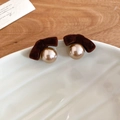 Dettaglio orecchini a fiocco floccato marrone con perla champagne su bordo ceramico - Marrone