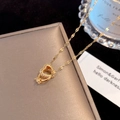 Close-up of golden interlocking heart necklace with zircon inlay on a jewelry box - Gold Heart Ring (Lip Chain)