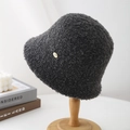 Close-up of deep gray faux shearling bucket hat fabric with a round metal logo detail - Gray
