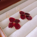 Dettaglio di orecchini a goccia rossi con bordo dorato su una scatola di velluto beige - Gancio per Orecchio-Rosso