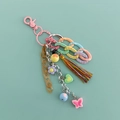 Macro detail of acrylic chain keychain with cotton tassels and mixed color charms - Pink