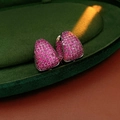 Makroaufnahme silberner C-Ohrringe mit pavé-gefassten rosa Zirkonia-Steinen - Schwarz und Lila