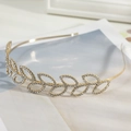 Nahaufnahme eines goldenen Blatt-Hairreifens mit Strasssteinen auf einem Magazin - Goldener Blattstil (C8308)