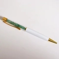 Dettaglio di una penna a sfera bianca con fusto trasparente riempito di pietre di cristallo verdi - Refill Nero 14cm / Giada avventurina