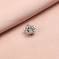 Close-up of a silver stainless steel rose flower bead on a soft pink textile background - 5mm Rose Flower Style