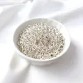 Shiny silver open jump rings in a ceramic bowl on white silk for DIY jewelry making - 3mmx0.5mm (50 Pcs) / Sterling Silver Color