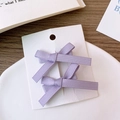 Détail de deux nœuds à cheveux en satin violet sur carte, style balletcore élégant - Violet