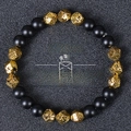 Detailed top view of black matte beads and gold faceted stones wealth bracelet on texture - Matte Black Gold Lava Stone Style (Wealth-8)