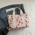 Pink corduroy tote bag featuring strawberry patterns and white woven handles - Pink