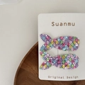 Macro detail of sparkly sequin mermaid scale hair clips for children on display card - Colorful