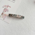 Macro shot of green and beige marbled acetate hair clip on a textured white surface - Milk Tea Green
