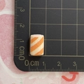 Makroaufnahme der winzigen orange-weißen Hot Pot-Zutat aus Harz, Abmessung ca. 1 cm - Crab-Stick