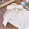 Elegant cream white satin bow hair clip with long ribbons on a decorative tray - Off White