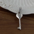 Pendentif clé en forme de cœur en acier inoxydable poli argenté sur fond en bois rustique - Clé du Cœur / Acier